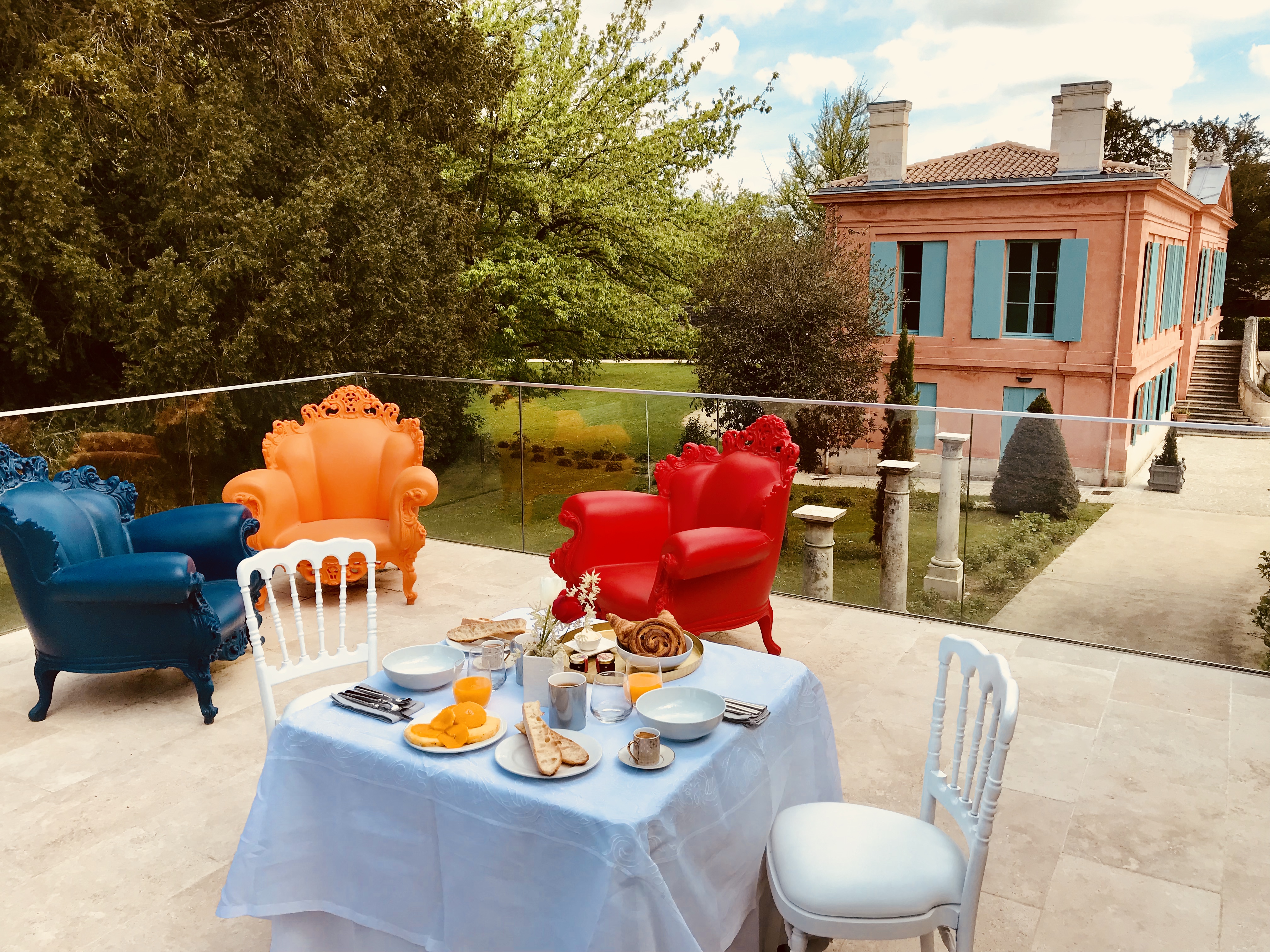 photo de la terrasse des chambres d'hôtes devant le château Pont St Martin, mise en scène avec une table dressée et fauteuils colorés