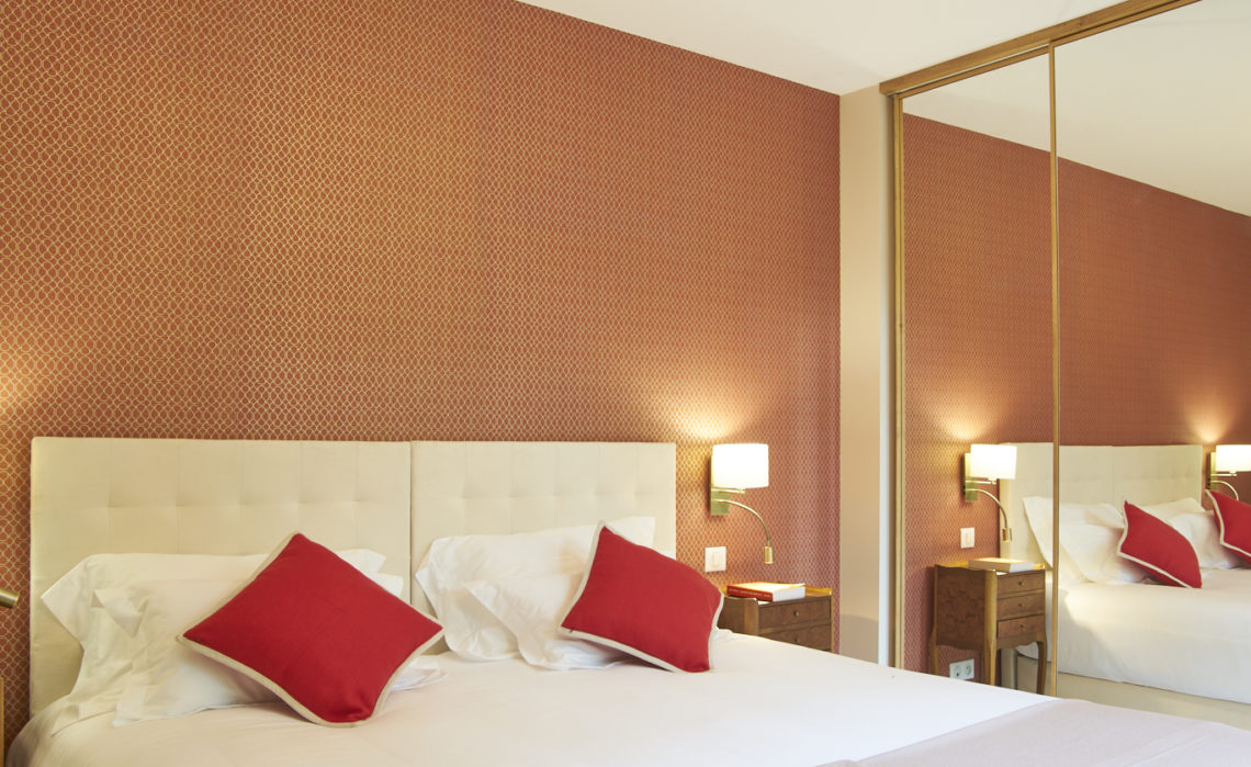 photo détail de la chambre Ausone, lit avec coussins rouge, tête de lit blanche et tapisserie ocre-rouge, chambres d'hôtes château Pont Saint-Martin, Pessac Léognan, Bordeaux, dégustation de vin, tout confort